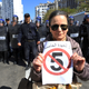 A woman poses with a sign reading "No to a 5th turn" in front of a line of police officers as she demonstrates with others to denounce President Abdelaziz Bouteflika's bid for a fifth term, Friday, March 1, 2019. Tens of thousands of protesters marched through Algeria's capital Friday against ailing President Abdelaziz Bouteflika's bid for a fifth term, surging past a barricade and defying repeated volleys of tear gas fired by police during the tense demonstration.